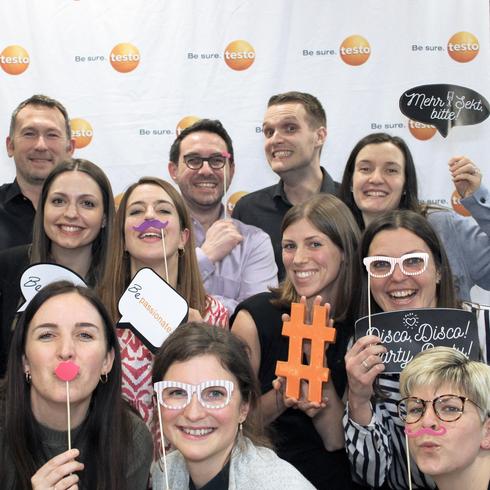 Testo is on a growth course and promotes specialists and executives An employee and a female employee of Testo work together at their desks and look into the camera together.