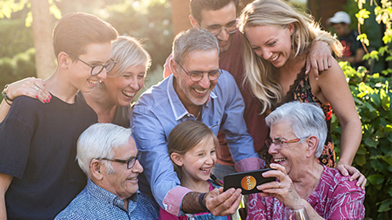 Different generations enjoy their free time, laughing and looking at a smartphone.
