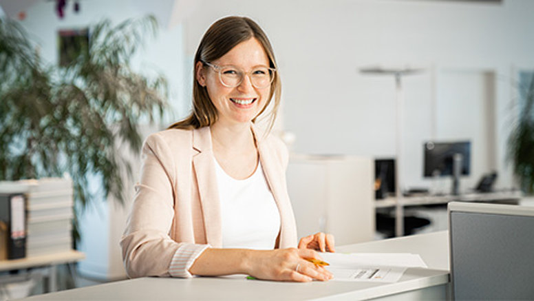 We are reliable! - Our values We are reliable - employee at desk, laughing into the camera.