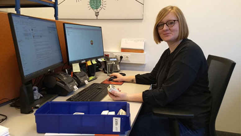We bear responsibility - Our values We bear responsibility - employee sits at desk and smiles.